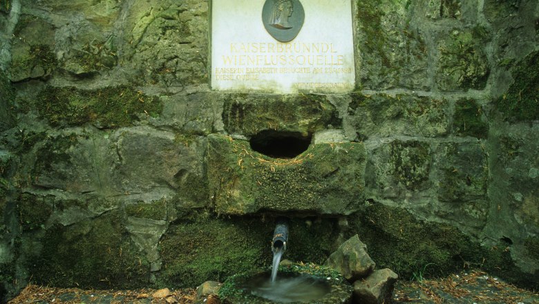 Kaiserbründl, © Kaiserbründl Steinbrunnen mit Inschrift 'Kaiserbründl Wienflussquelle'. Wasser fließt aus einem Rohr in eine Schale.