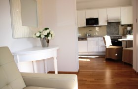 Altes Pförtnerhaus, © © Elisabeth Hofer Innenansicht eines modernen Wohnbereichs mit Küche und Blumen auf einem Tisch.