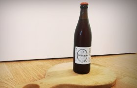 Weizenbier vom Holzbräu, © Wiener Alpen Eine Flasche Weizenbier vom Holzbräu steht auf einem runden Holzbrett mit Griff.