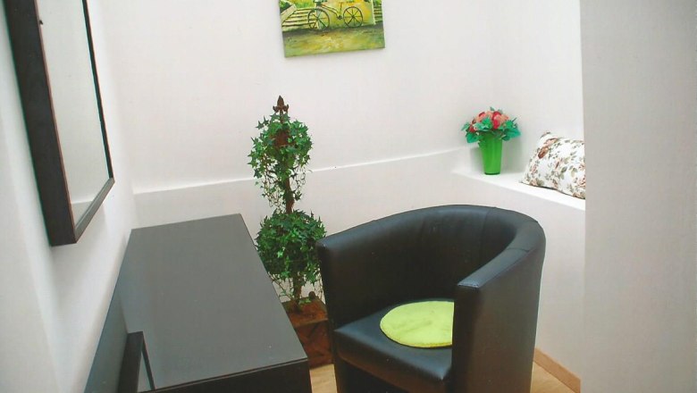 Gästezimmer Weixelbaum, © Weixelbaum Kleines Gästezimmer mit schwarzem Sessel, grünem Kissen, Spiegel, Pflanzen und Wandbild.