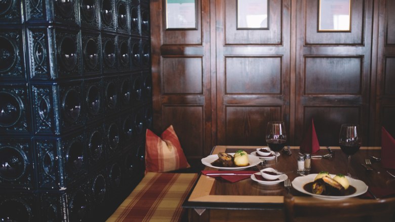 Urige Gaststube, ruhiger Gastgarten, © Niederösterreich Werbung/Mara Hohla Gemütliche Gaststube mit Holzwänden, gedecktem Tisch und Kachelofen.