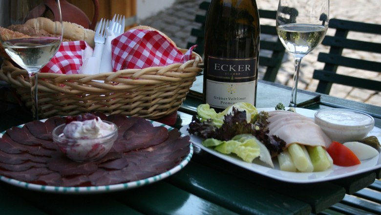 Jausentisch, © Ecker Ein gedeckter Tisch mit Wein, Brot, Aufschnitt und Salat.