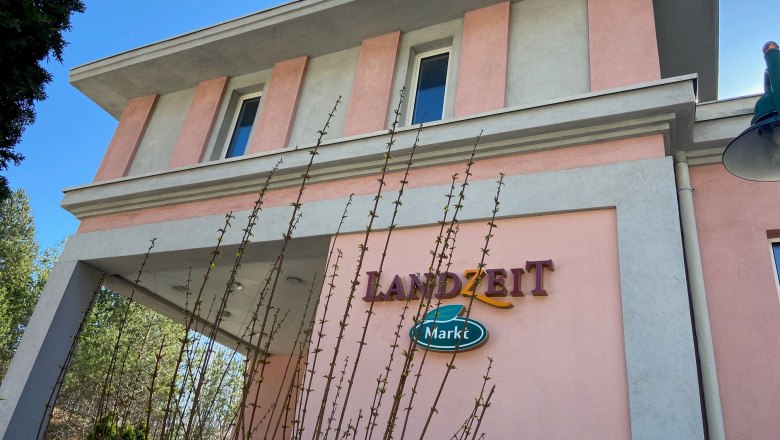 Landzeit Schottwien, © Wiener Alpen Gebäude mit rosa und grauer Fassade, Schriftzug 'Landzeit Markt'.