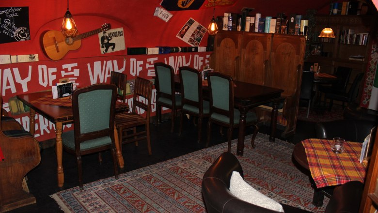 Sitznische im hinteren Bereich, © Mary´s Scottish Coffeepub Gemütliche Sitzecke in einem Café mit Holzmöbeln und Dekorationen an den Wänden.