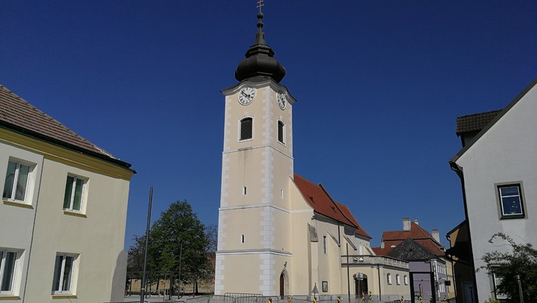 Kirche in Rohrendorf, © Roman Zöchlinger Kirche mit Turm und Uhr in Rohrendorf vor blauem Himmel.