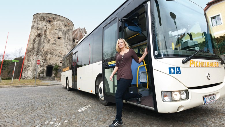 Autofrei unterwegs in der Wachau, © Steve Haider Eine Frau steigt aus einem Bus in der Wachau aus, im Hintergrund ein historischer Turm.