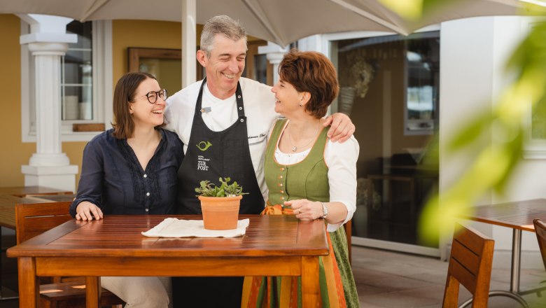 Elisabeth, Johannes und Margarete Ebner, © Niederösterreich Werbung/Daniela Führer Fam. Ebner, die Inhaber des Hotel Zur Post, stehen um einen Tisch im Freien.