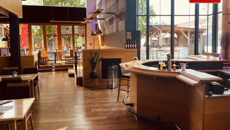 Brauhaus Schwechat, © Brauhaus Schwechat Innenansicht eines modernen Brauhauses mit Holzmöbeln und großen Fenstern.