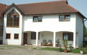 Weingut Wagner, © Fam. Wagner Ein zweistöckiges weißes Gebäude mit roten Dachziegeln und großen Fenstern. Vor dem Haus stehen Pflanzen in Töpfen.