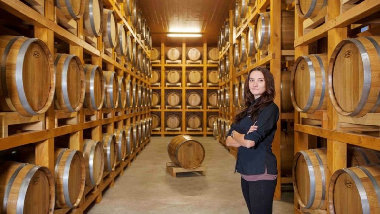 Jasmin Haider, © Whisky-Erlebniswelt Haider, Harald Eisenberger Eine Frau steht in einem Lagerraum mit vielen Holzfässern auf Regalen.