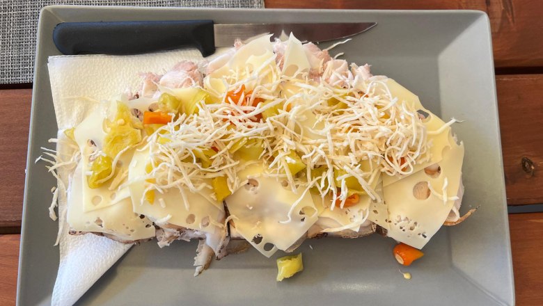 Dorfheuriger Muhr Stixneusiedl, © Donau Niederösterreich Ein Käsebrot mit Gemüse und geriebenem Kren auf einem grauen Teller.