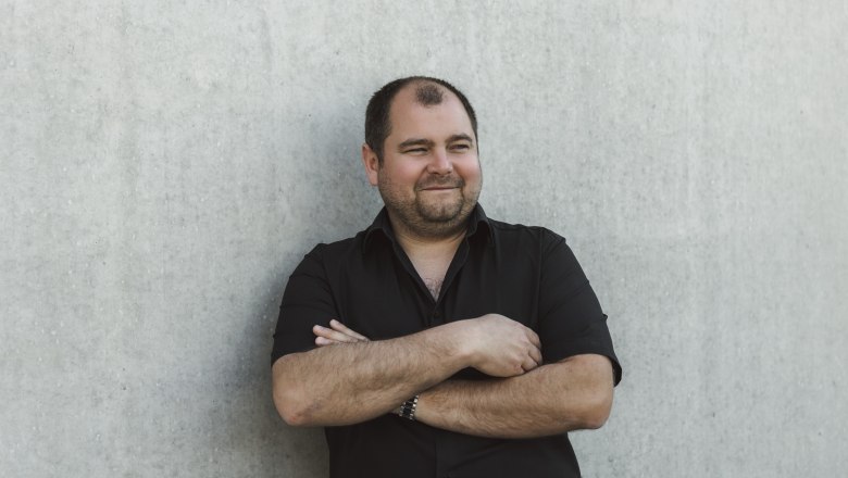 Peter Kerschbaummayr, © Niederösterreich Werbung/David Schreiber Mann in schwarzem Hemd lehnt an einer Betonwand.