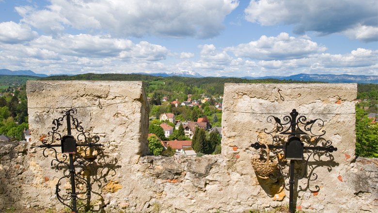 Panorama Bergkirche, © Marktgemeinde Pitten Aussicht von einer alten Steinmauer auf eine ländliche Landschaft mit Bergen im Hintergrund.