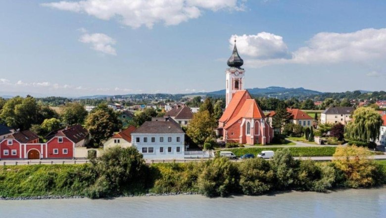 Ansicht Persenbeug-Gottsdorf, © Guestia GmbH Landschaftsansicht von Persenbeug-Gottsdorf mit Kirche und Fluss im Vordergrund.