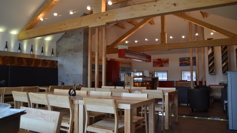 Weinbau Müllner, © Michael Müllner Innenansicht eines modernen Weinguts mit Holzbalken, Tischen und Stühlen.