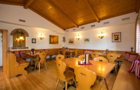 Stube, © Wein und Heuriger Ganneshofer Gemütliche Stube mit Holzmöbeln, karierten Kissen und Wanddekorationen.