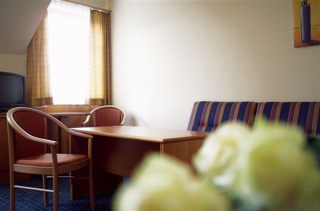 Eisenbocks Strasserhof_Zimmer, © Eisenbock's Strasser Hof Hotelzimmer mit Tisch, Stühlen und Sofa.