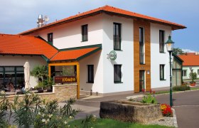 Haus aussen, © Scheumbauer Außenansicht eines Gebäudes mit rotem Dach und Terrasse, beschriftet mit 'caffè e vini Centro'.