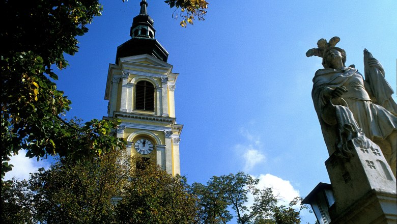 Pfarrkirche Großweikersdorf, © Donau Niederösterreich Turm der Pfarrkirche Großweikersdorf mit Statue im Vordergrund.