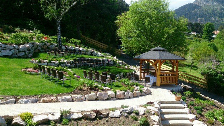 Panoramagarten mit Hochzeitspavillon, © Schubertlinde Ein gepflegter Garten mit einem Hochzeitspavillon, umgeben von Stühlen und grüner Landschaft.