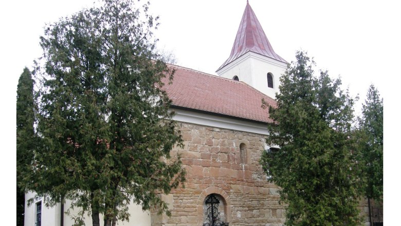 Kirche, © Gemeinde Pernersdorf Historische Kirche mit rotem Dach und Turm, umgeben von Bäumen.