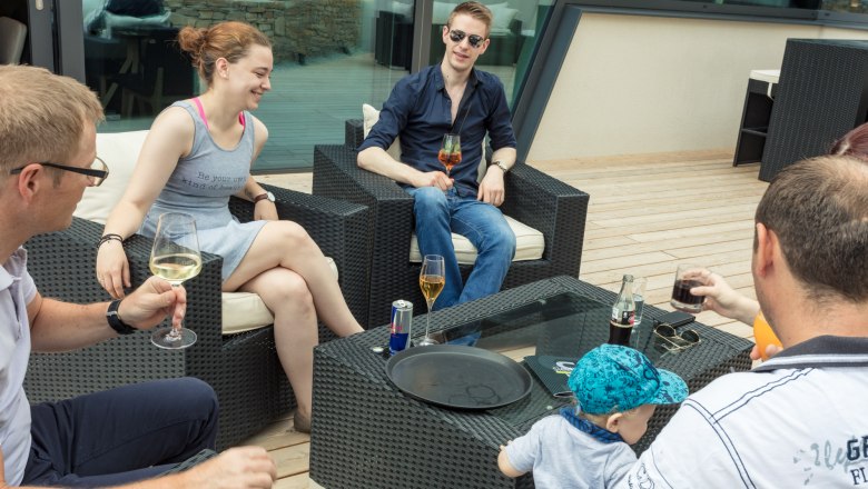 Gesellige Runde auf der Terrasse, © KASTNER NEW MEDIA - kastner.tv Gruppe von Menschen sitzt auf einer Terrasse und trinkt Getränke.