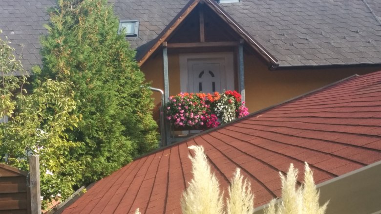 Zugang auf der Panoramatreppe, © Reep Hausdach mit rotem Schindeldach, Balkon mit Blumen, Baum im Hintergrund.