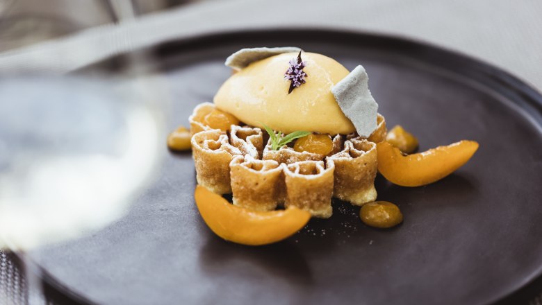 Weinser Waffel mit Marillensorbet, © Niederösterreich Werbung/David Schreiber Eine kunstvoll angerichtete Waffel mit Marillensorbet und dekorativen Früchten auf einem schwarzen Teller.