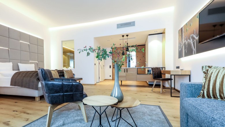 Aussenpool-ansicht-von-oben, © Klinglhuber Modern eingerichtetes Hotelzimmer mit Bett, Sesseln, Tisch und Dekoration.