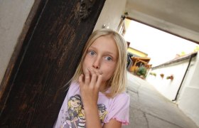 Hereinspaziert, © Fam. Schwalm Ein Mädchen steht in einem Torbogen und schaut überrascht in die Kamera.