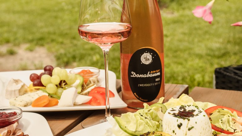 Jause beim Strawanzer, © Rita Newman Ein gedeckter Tisch im Freien mit Wein, Salat und Käseplatte beim Heurigen Strawanzer