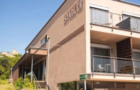 Weingut Stadler, © Georg Wilke Modernes Gebäude des Weinguts Stadler mit Terrasse und Burg im Hintergrund.