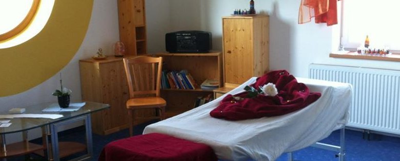 Massageraum, © Landgasthof Oppolzer Ein gemütlicher Massageraum mit Massageliege, Holzregalen und einem großen runden Fenster.