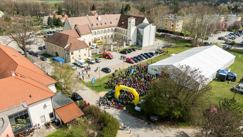 Schloss Katzelsdorf bei der Rosalia Trail Challenge, © Wiener Alpen/Martin Fülöp Luftaufnahme eines Schlosses mit Menschenmenge, Zelten und Gebäuden, während der Rosalia Trail Challenge.