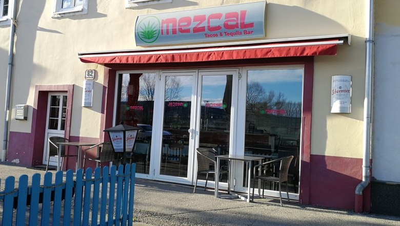Mezcal Restaurant, © Roman Zöchlinger Außenansicht des Mezcal Restaurants mit roten Markisen und Sitzgelegenheiten.