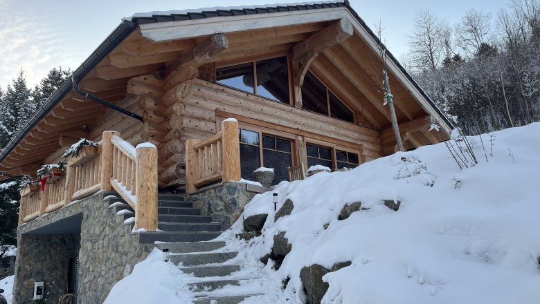 RaxChalet im Winter, © RaxChalet Ein Holzchalet im Winter mit Schnee bedeckt, umgeben von Bäumen.