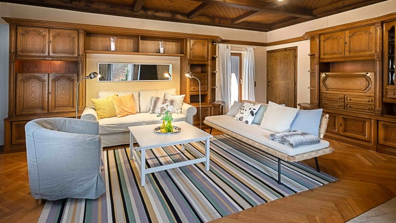 Top 1 - Wohnzimmer, © VP FeWo OG Gemütliches Wohnzimmer mit Holzmöbeln, Sofas, Teppich und Couchtisch.