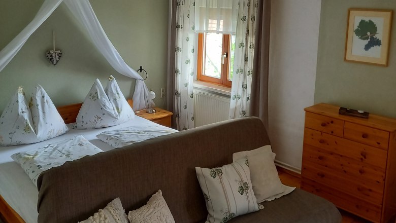 Gästezimmer, © Familie Fleischmann Gemütliches Gästezimmer mit Doppelbett, Sofa und Holzmöbeln.