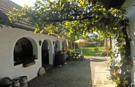 Gasthof Kramreiter, © Familie Kramreiter Ein gemütlicher Gasthof mit weißen Bögen, grüner Laube und gelben Sonnenschirmen im Garten.