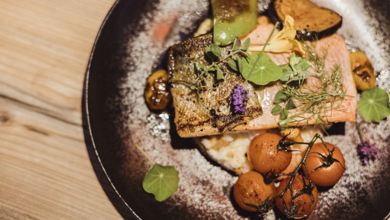 Lachsforellenfilet auf Grammelrisotto mit Gemüse, © Niederösterreich Werbung/David Schreiber Lachsforellenfilet auf Grammelrisotto mit Gemüse und Kräutern auf einem Teller.