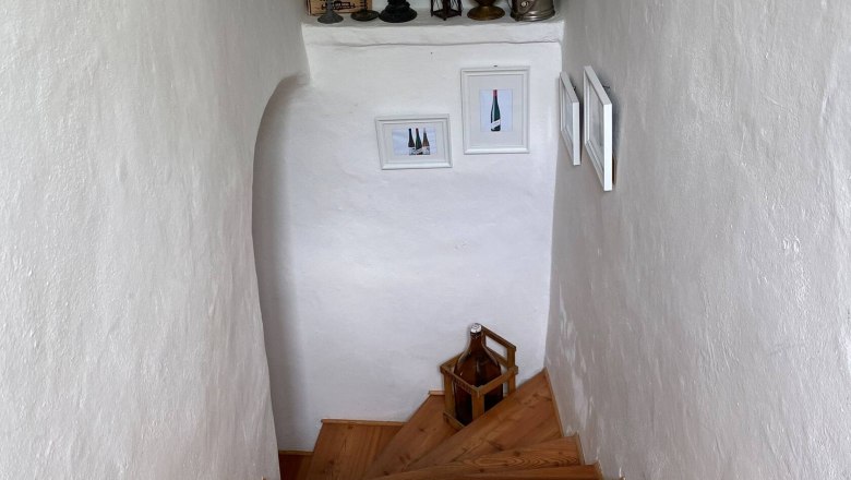 Treppenhaus, © Familie Stagard Holztreppe in einem weißen Treppenhaus mit Dekorationen und Bildern an den Wänden.