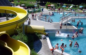 Parkbad Haag, © zVg Gemeinde Haag Ein Freibad mit gelber Wasserrutsche, Schwimmern im Becken und Menschen auf der Liegewiese.