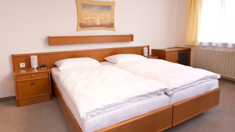 Zimmeransicht, © Gasthof zur Sonne Ein Hotelzimmer mit einem Doppelbett, Holzmöbeln und einem Bild an der Wand.