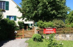 Haus, © Pension Lindenhof Ein Haus mit Garten und einem Schild "Pension Lindenhof" am Holzzaun.