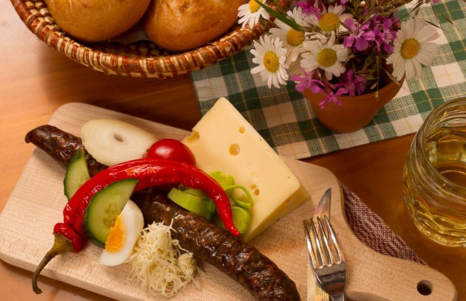 Jause, © © Langthaler Ein traditionelles Jausenbrett mit Wurst, Käse, Gemüse und Brot auf einem Holztisch.