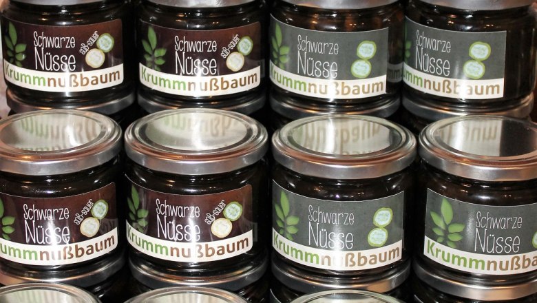 5-schwarze-nuesse, © Johann Peham Mehrere Gläser mit der Aufschrift 'Schwarze Nüsse Krummnußbaum' auf einem Tisch gestapelt.
