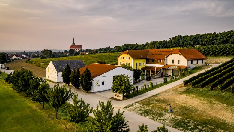 Weingut Neustifter, © Weingut Neustifter Luftaufnahme eines Weinguts mit Gebäuden und Weinbergen bei Sonnenuntergang.