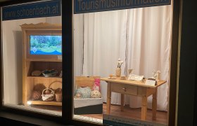 Infostelle Schönbach, © Marktgemeinde Schönbach Schaufenster mit Tourismusinformationen und handgefertigten Produkten.