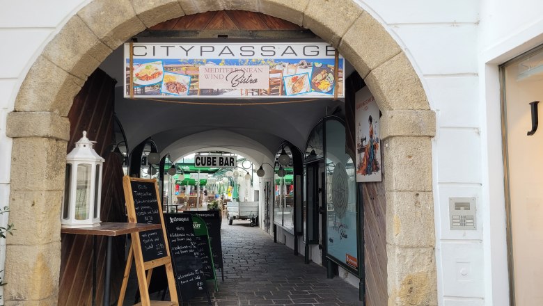 TDR-Mediteranean Wind Bistro, © DNÖ Ketting Eingang zur Citypassage mit Schildern für ein Bistro und eine Bar.