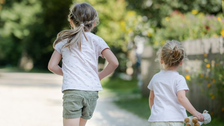 Kinder beim Spielen, © Niederösterreich Werbung / Claudia Schlager Zwei Kinder laufen auf einem Kiesweg in einem Park, umgeben von Bäumen und Blumen.
